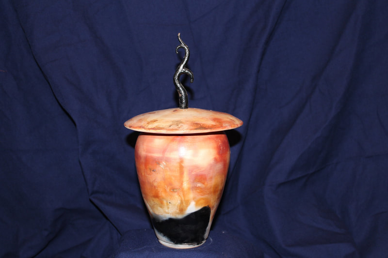 orange and black raku fired pot and lid with metal antler-like handle